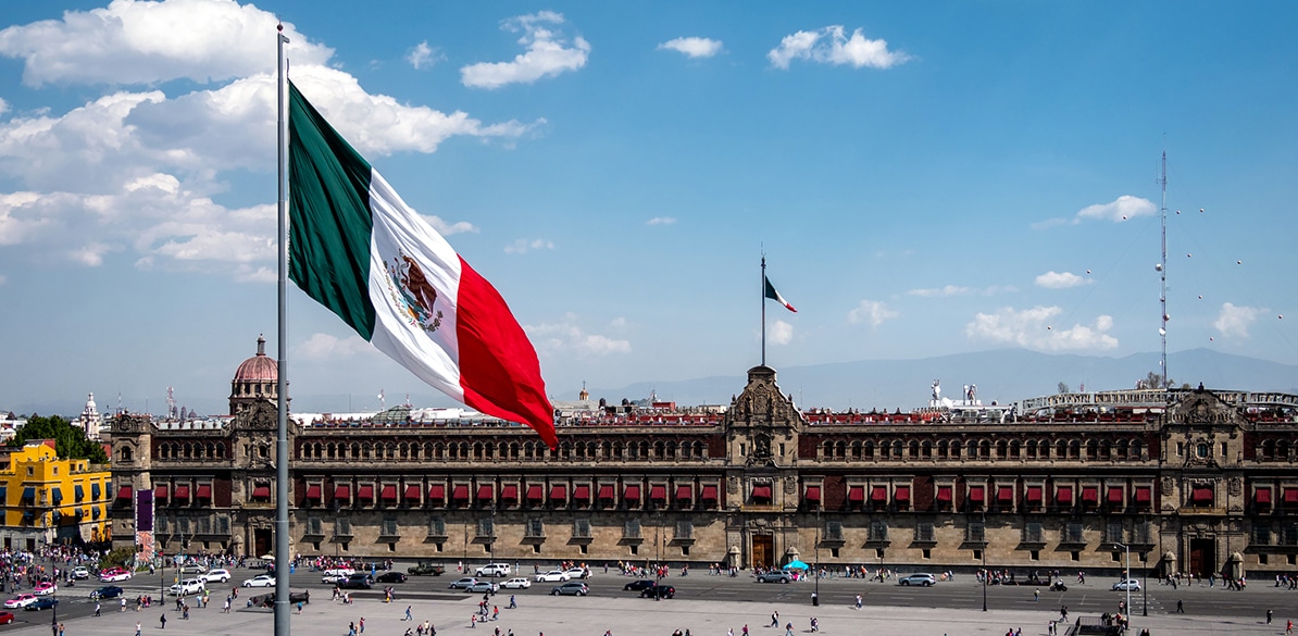 Vista de la Plaza Mayor en Ciudad de México con la bandera de México ondeando, representando el espíritu solidario que une a la nación en la celebración del Día Internacional de la Solidaridad Humana.