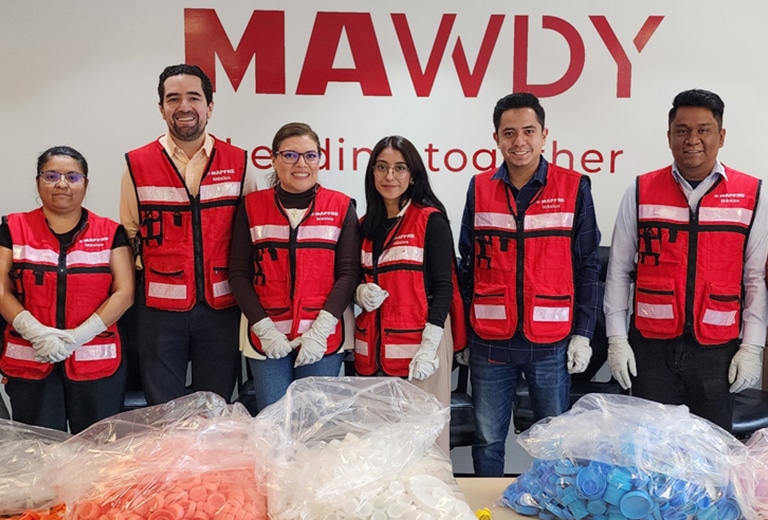 Voluntarios de Fundación Mapfre México con chalecos rojos clasificando tapones de plástico para reciclaje